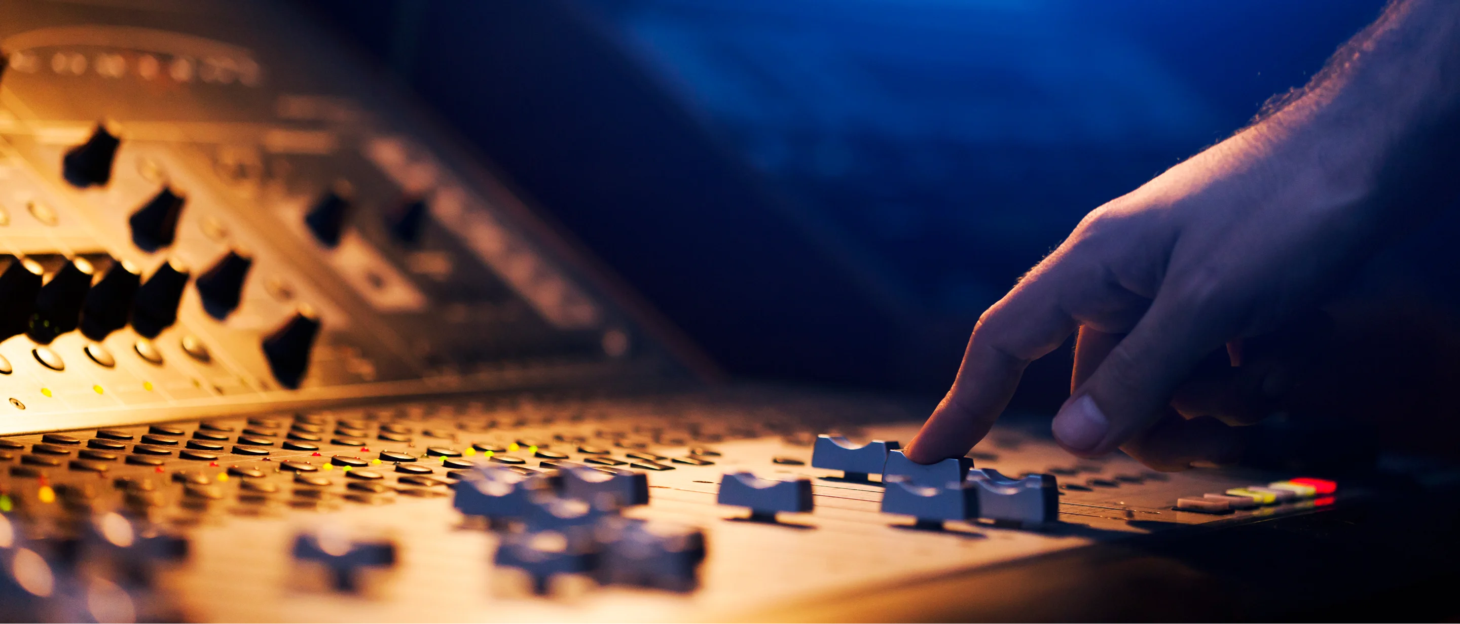 Hand adjusting audio mixing console faders