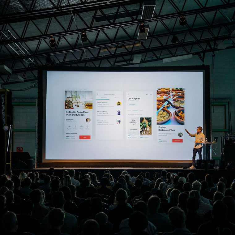 Presenter giving app demo to large audience